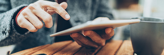 Photo of a hand holding a tablet displaying National Bank news