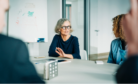 Photo of a woman speaking to their colleagues in a conference room