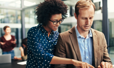 Photo of a man and woman consulting documents in a glass office