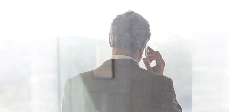 Photo of the back of a man who is speaking on the phone  