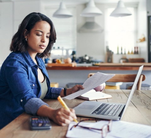 Photo d’une femme assise à une table qui travaille sur son ordinateur portable