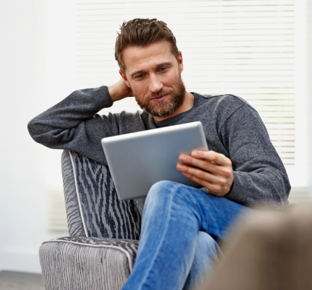 Photo d’un homme assis dans un fauteuil qui consulte sa tablette