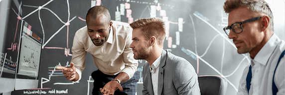 Photo of three men talking in front of a computer
