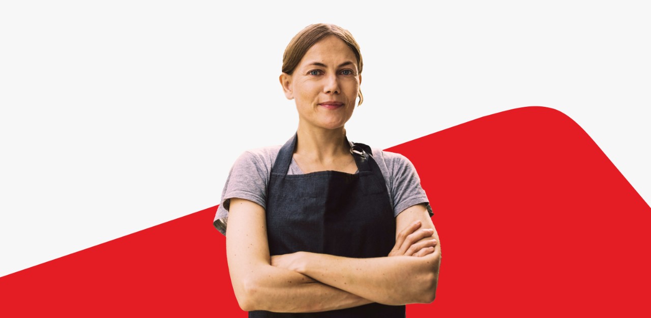 Photo of an entrepreneur with their arms crossed standing in front of the National Bank logo 
