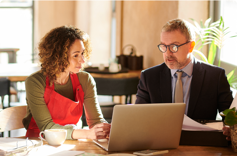 Photo of an entrepreneur and an account manager looking at a laptop in a coffee shop 