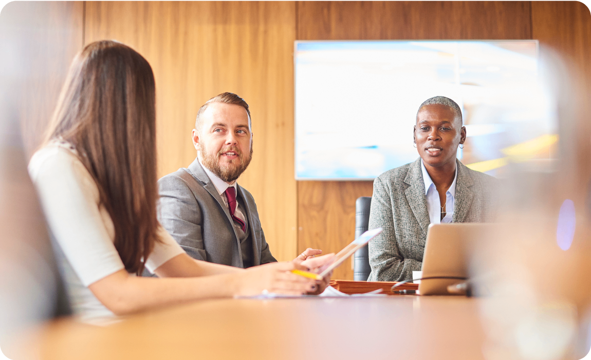 Photo of a group of people speaking in a conference room 