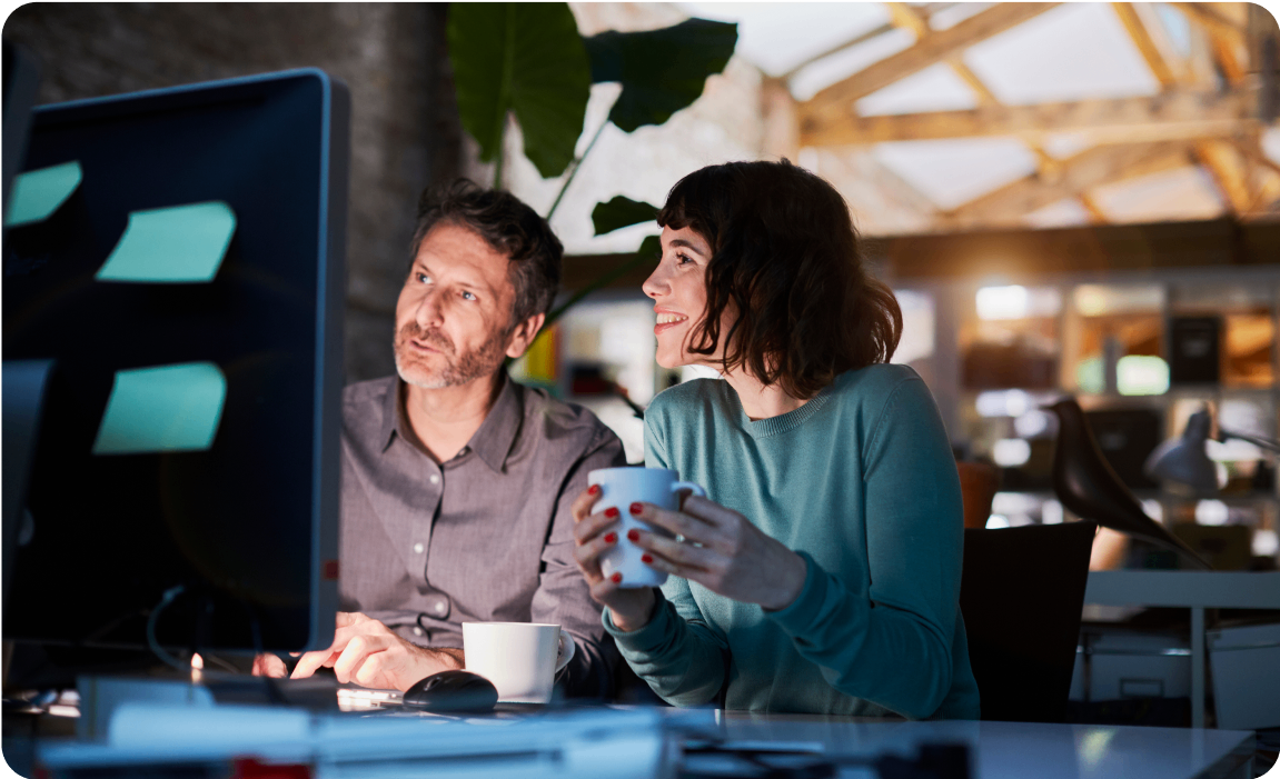 Photo of two people working while looking at a computer screen 