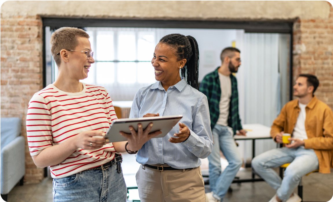 Photo of two people talking while looking at a tablet 