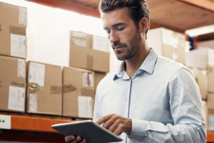 Picture of a man in a warehouse looking at his tablet 