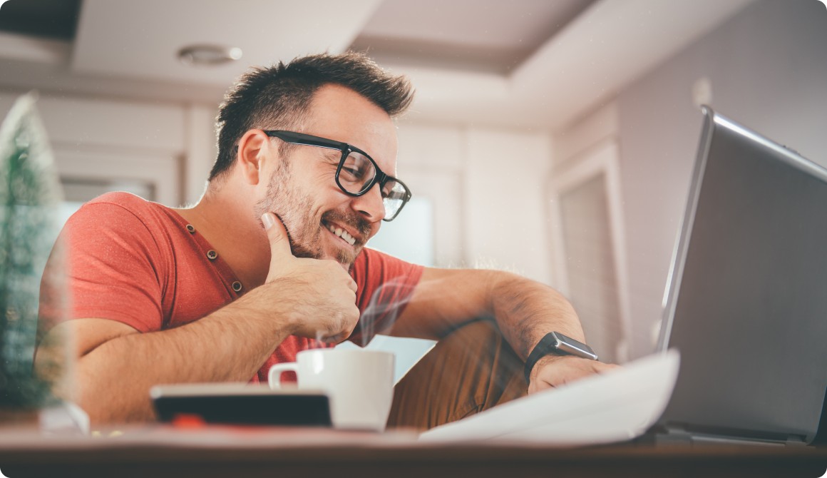 Picture of a man in front of his computer with a coffee