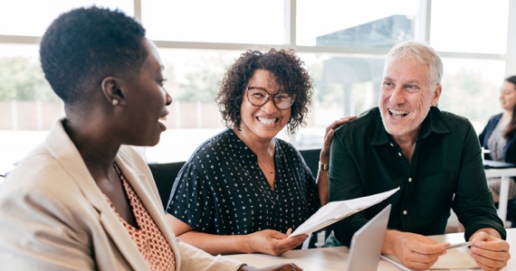 Photo of three professionals having a conversation at a conference table