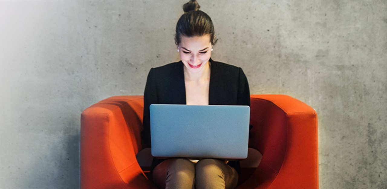 Photo of a woman sitting in a chair working on her laptop