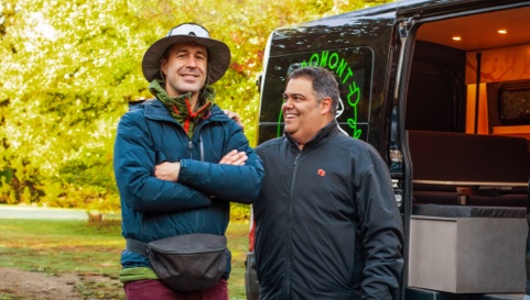 Photo of a National Bank advisor and their client smiling next to a minivan equipped for camping 
