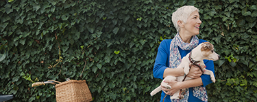 Woman holding her dog next to her bicycle