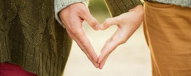 Man and woman make a heart shape with their hands