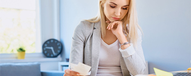 Woman is thinking while looking at her bills