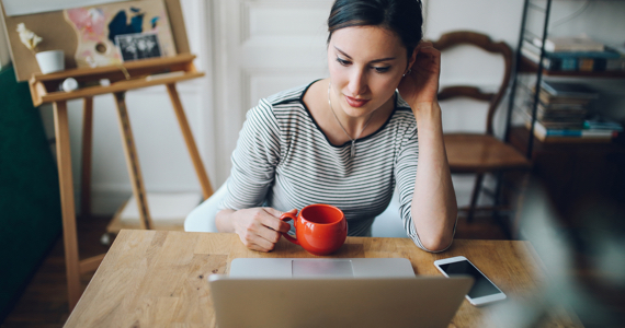 Young woman sitting at a table looks at her computer