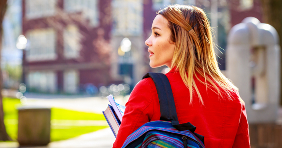 Young female student with backpack walking on university campus