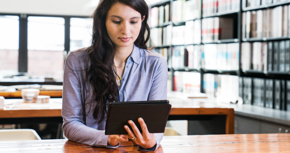 Young woman in library looking at her tablet