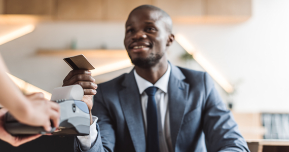 Young man hands a bank card to a saleswoman