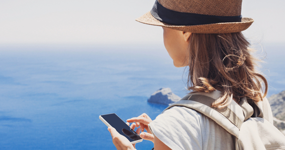 Woman on vacation by the sea using her phone