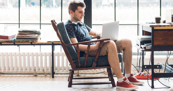 Student sitting with headphones around his neck looking at his computer screen