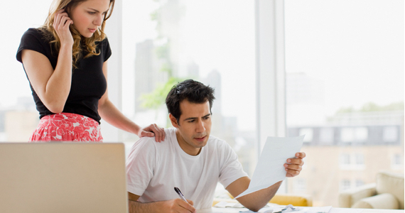 Standing woman puts her hand on the shoulder of a seated man who shows her a document