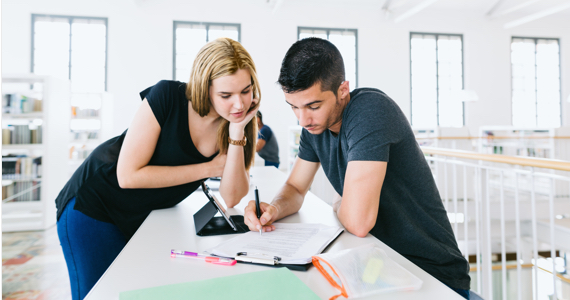 Young female student and young male student are looking at a document