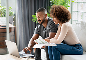 Couple sitting on a sofa looking at a laptop