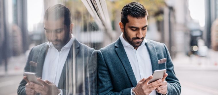 Photo of a man looking at his phone in front of an office building