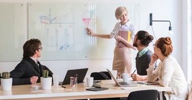 Four people discuss a diagram in a conference room