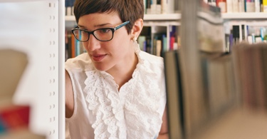 Young woman looking for a book in a library