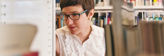 Young woman looking for a book in a library