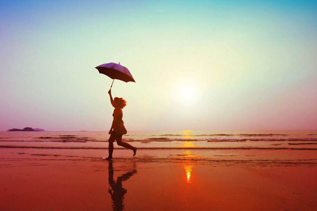 Young woman running on the beach with the sun setting in the horizon