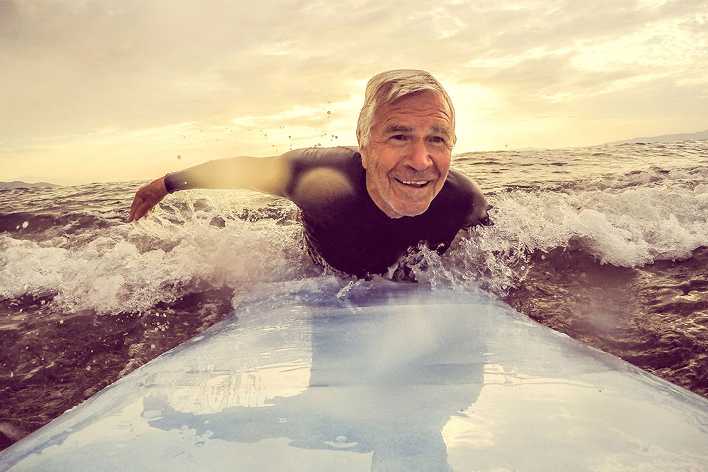 Retired man smiling on a surfboard