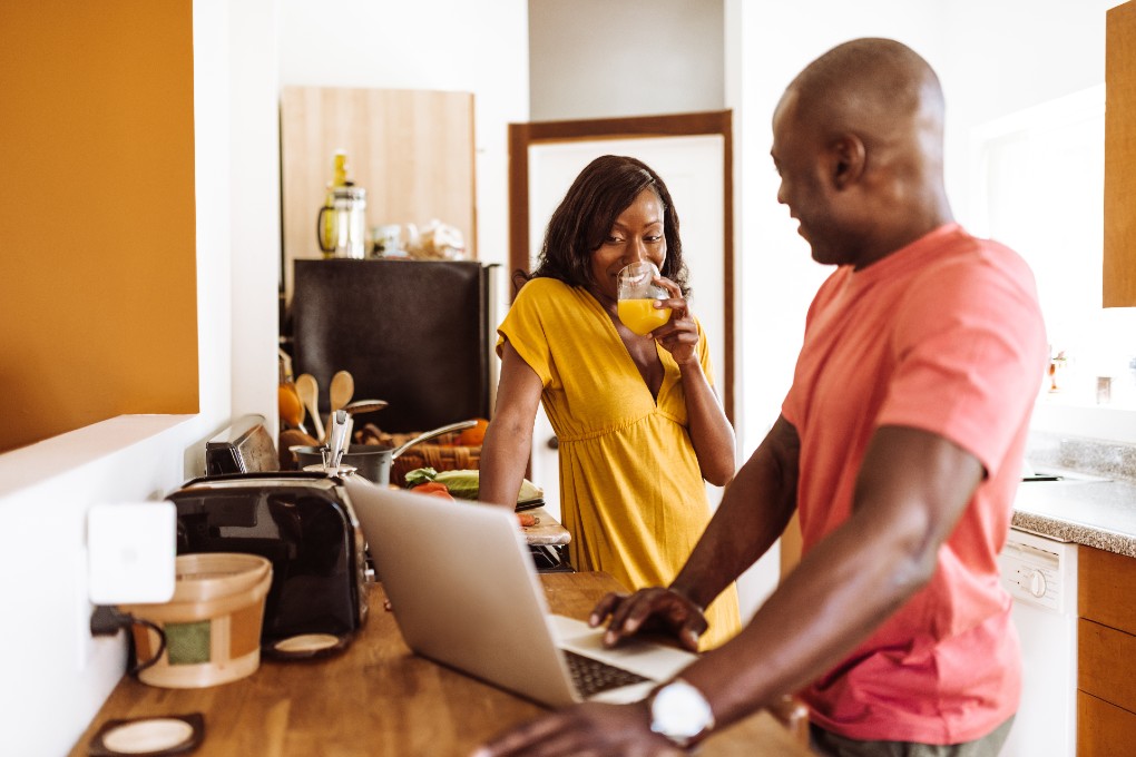 Image d'un couple discute dans la cuisine tout en naviguant sur le Web.