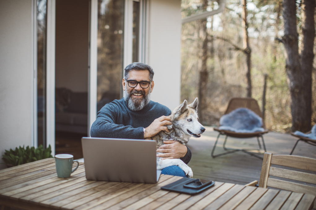 Man standing and smiling in front of his computer.