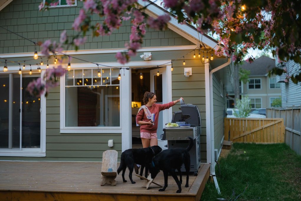Woman standing by her BBQ on the patio of her new home