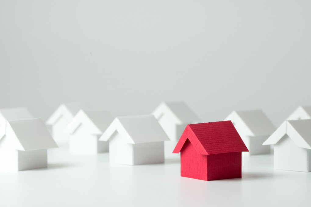 Image de plusieurs maisons en carton blanches et une maison rouge