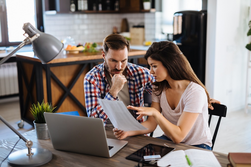 Un couple analyse l'état de leurs finances, assis à la table de la cuisine