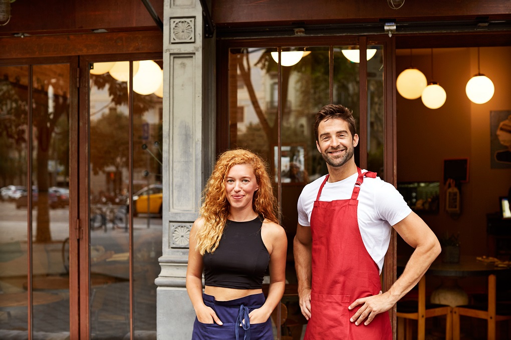 Franchise owners pose with a smile in front of their business.