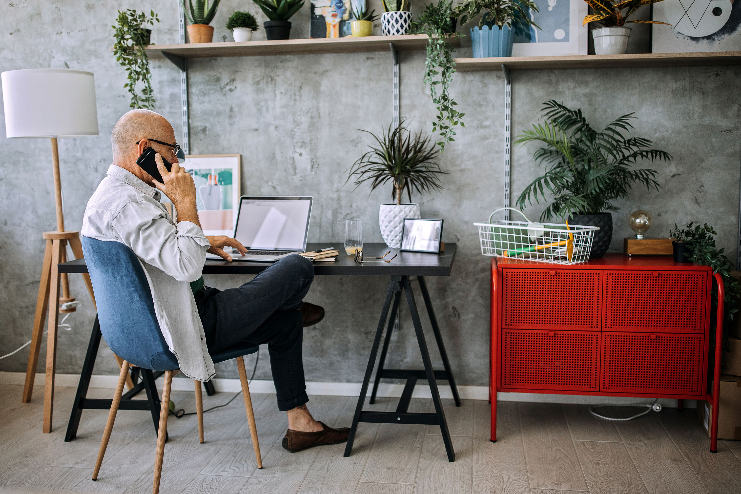 Entrepreneur, at his desk, talking on the phone about drawing down his investments in a holding company for his retirement