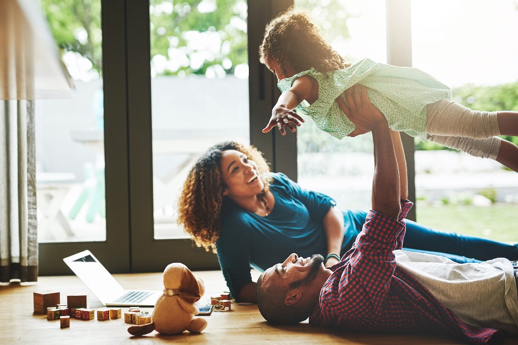 Common law partners playing with their child in the family room