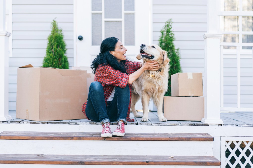 A young woman and her dog on the porch on her first home