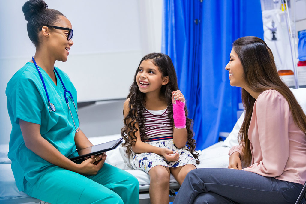 Photo of a young girl with her mother talking with a doctor 