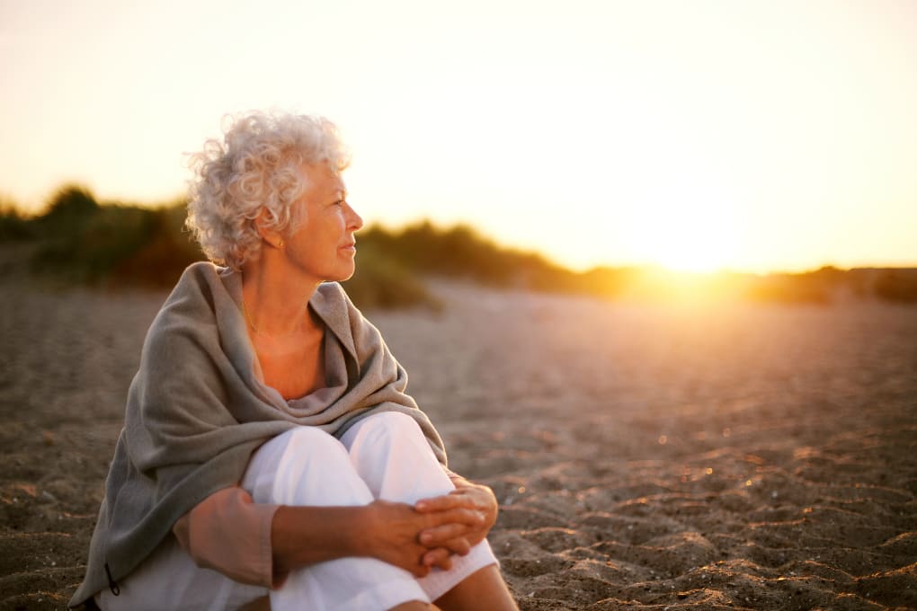 A retired woman enjoys the sunset on the beach in Florida