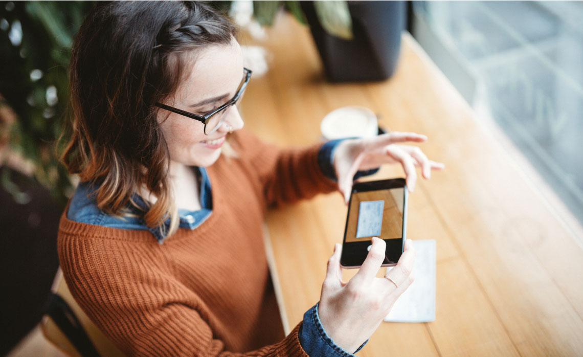 Photo of a woman taking a photo of her cheque with her mobile phone