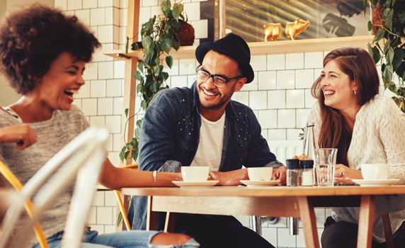 Three people sitting in a restaurant smiling