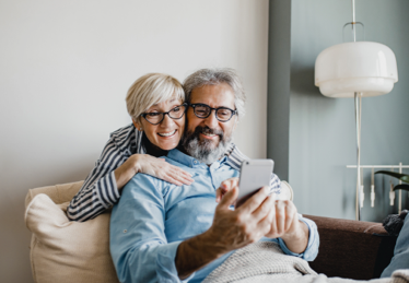 Photo of a smiling retired couple looking at a smartphone screen together