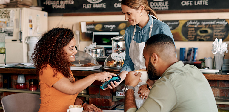 Photo of a woman paying her bill at a restaurant with her cellphone.